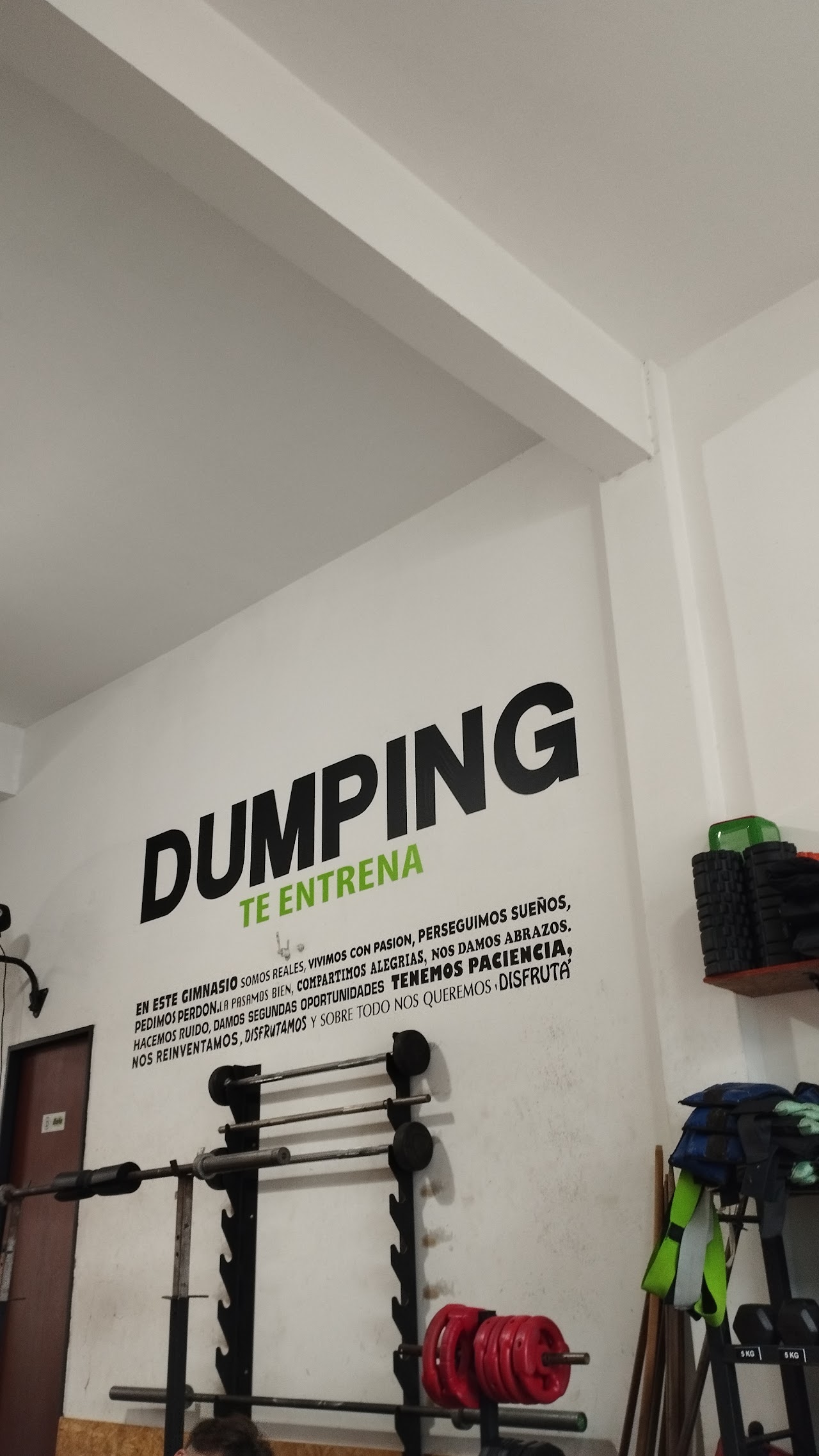 Entrenadora guiando postura y técnica de un atleta en sentadilla con kettlebell en Dumping Fitness